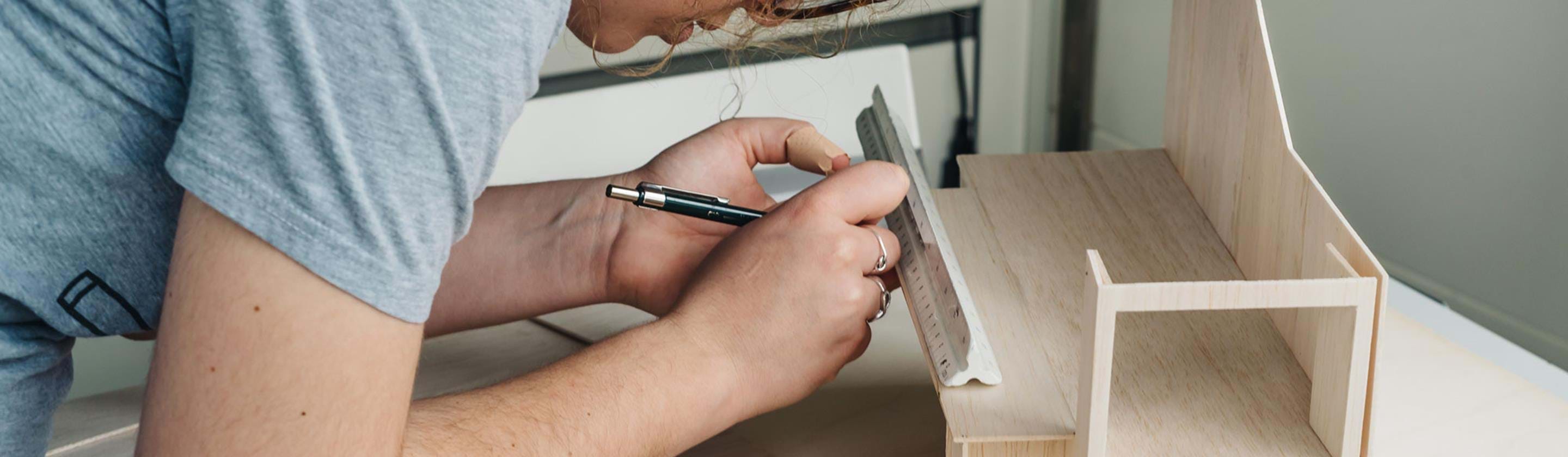 A person designing a wooden prototype of a building