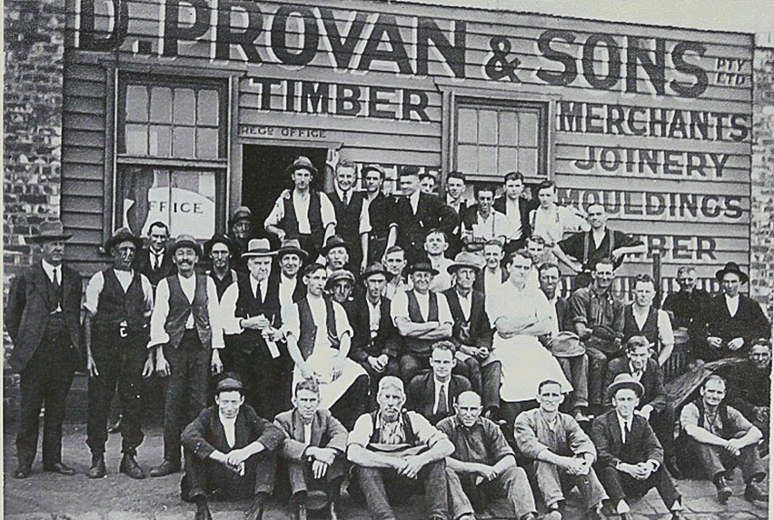 Old Black and White photo of D.Proven and Sons, with employees in a posing in a group out the front of the building