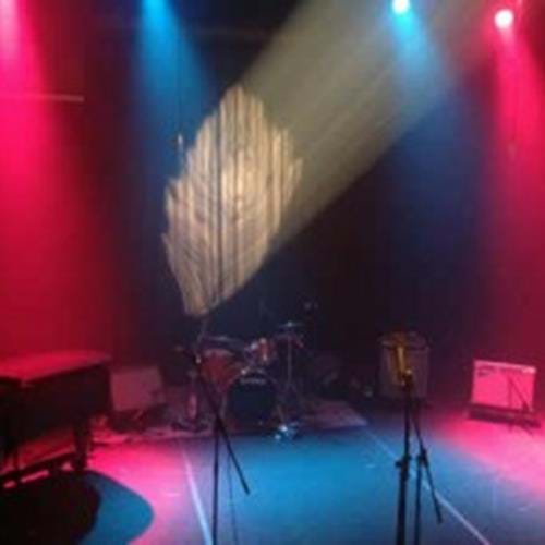 Stage setup with piano, microphones, drums, and speakers