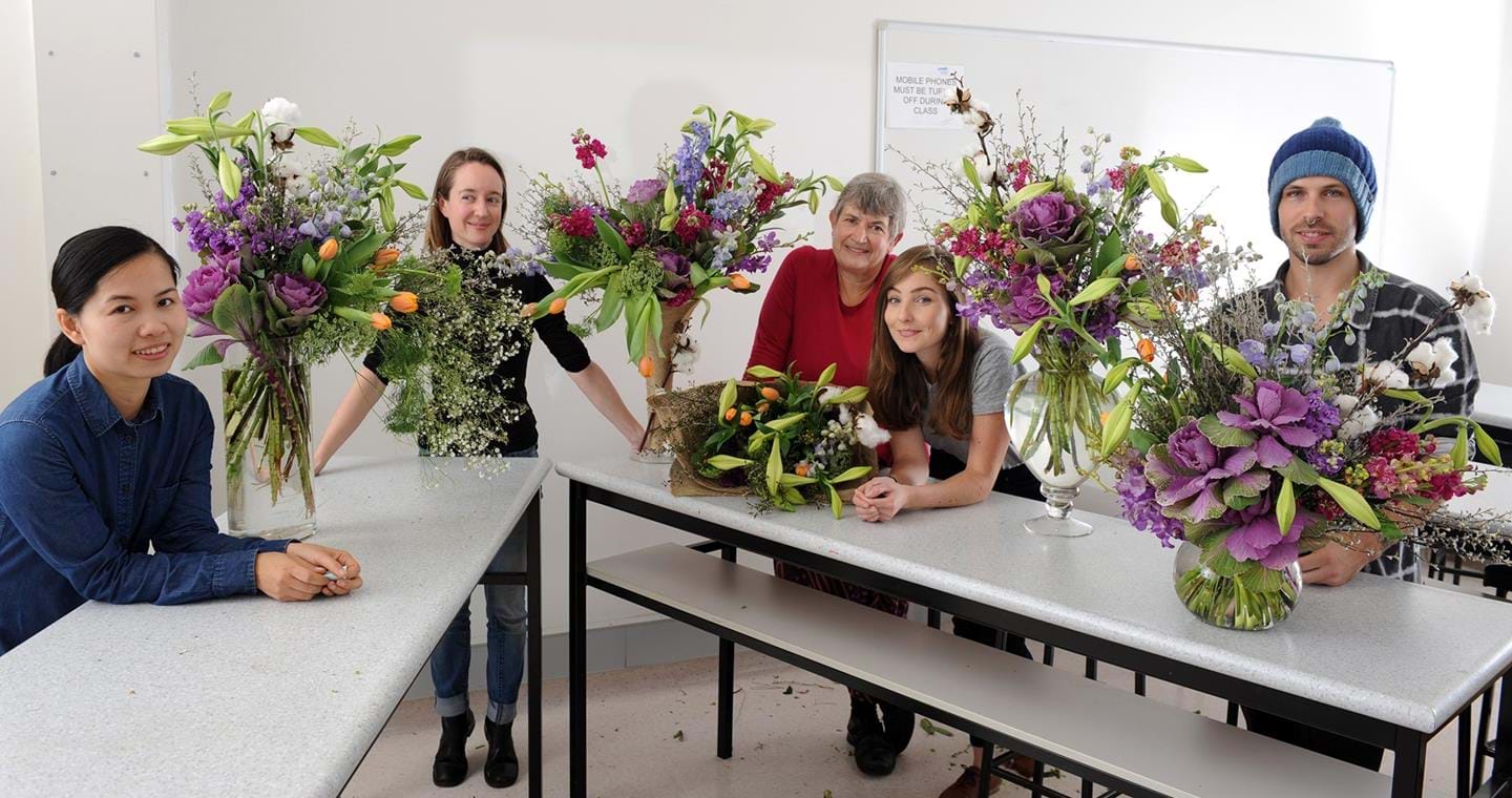 Floristy Studies students sitting at a table with their vase and bouquet floral arrangments
