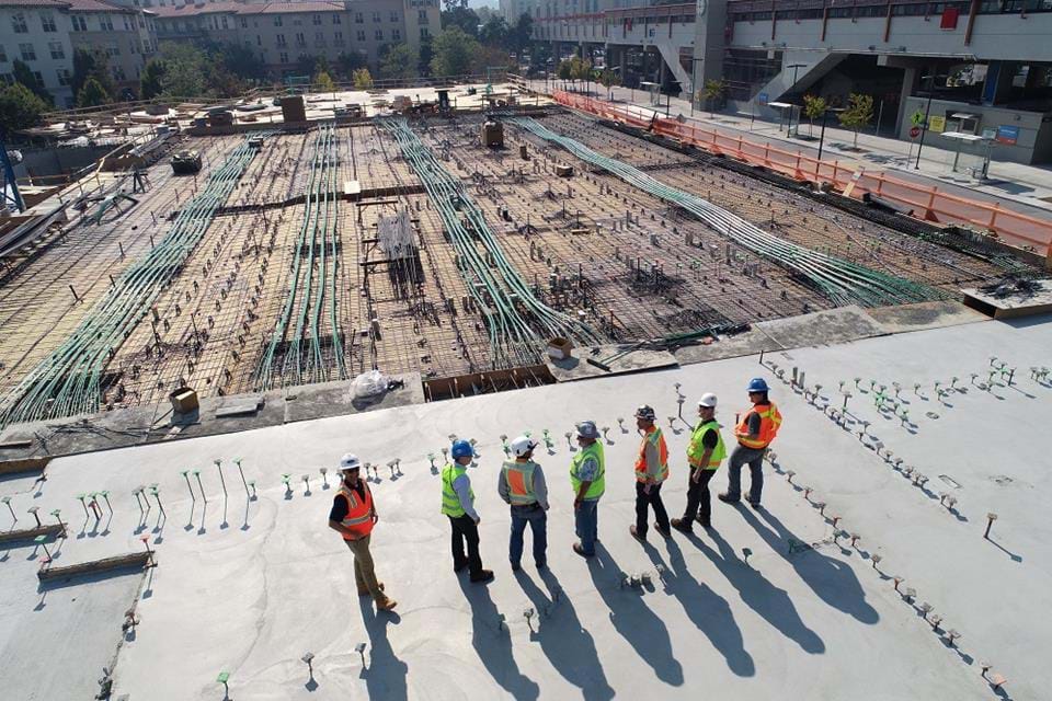 Workers standing next to a large construction site
