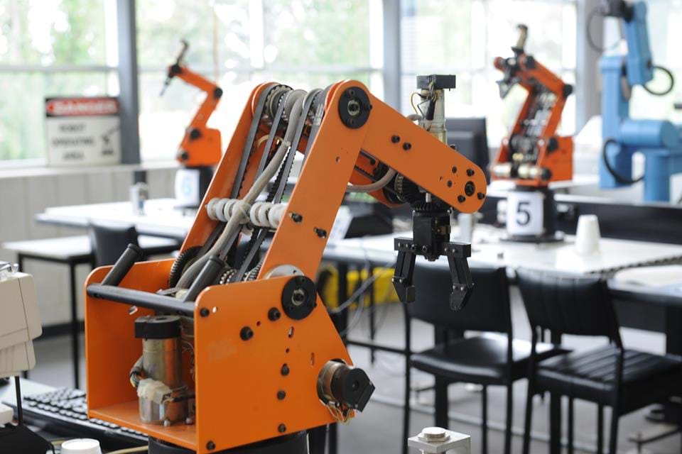 Large orange robotic arm used in manufacturing workshop